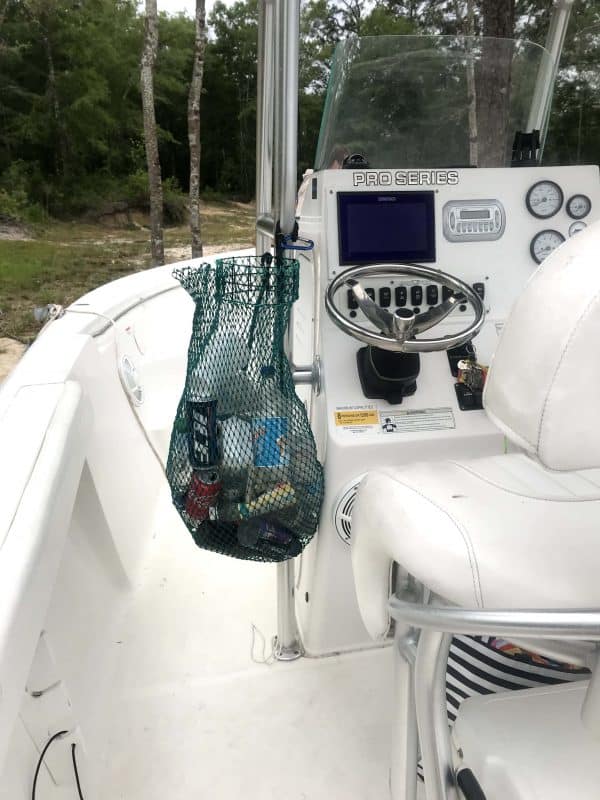 The Litter Gitter bag is full of trash and recyclables, hanging beside the captain's seat on a white boat.