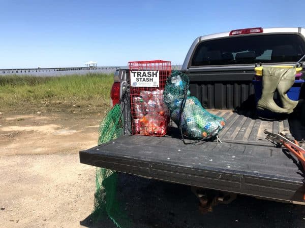 The Litter Gitter bag is full of empty drink bottles and laying in the back of a truck bed with the Osprey Trash Stash and Reusable Recycle Bag.