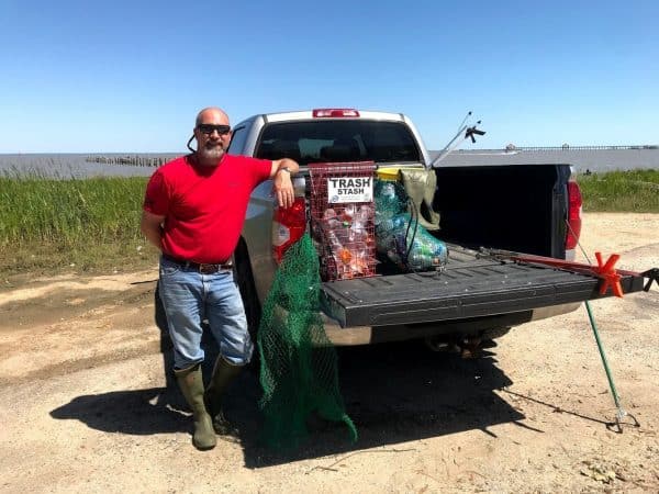 A man poses with his truck and the Osprey Reusable Recycle Bag and Trash Stash.